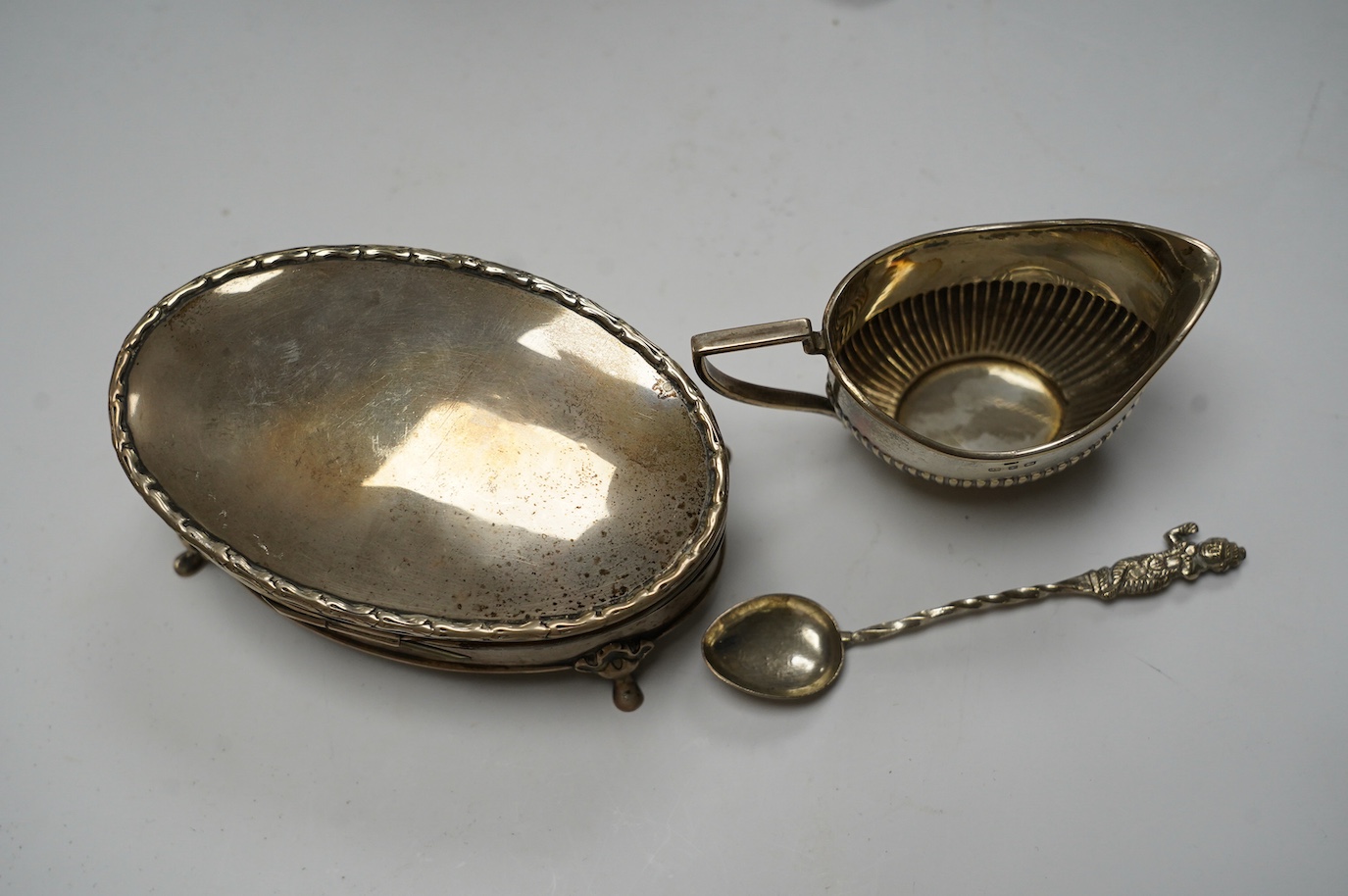 Small silver including a late Victorian pierced silver mustard pot, a small cream jug and oval trinket box, together with five metal spoons and a plated hot water jug. Condition - poor to fair